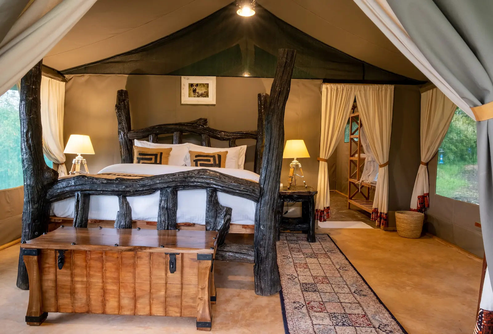 Deluxe Tent interior — driftwood four-poster bed, Persian runner, expedition chest