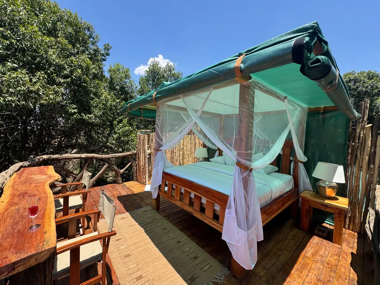 The Starbed deck in daylight — driftwood table, wine glass, the Mara plains beyond